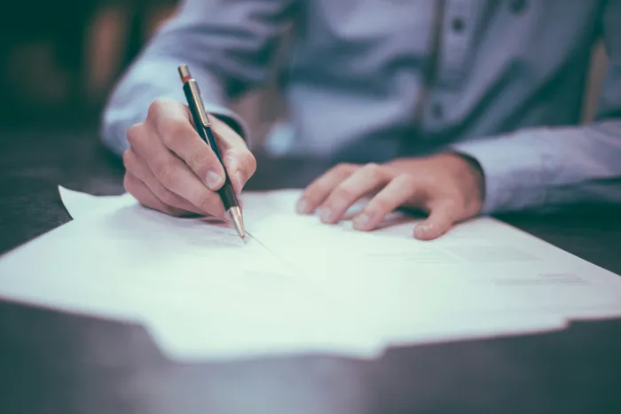 Firma de un documento, representando el cumplimiento legal y contractual